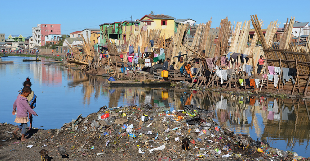 An image of two children standing on an island covered in polluted trash.
